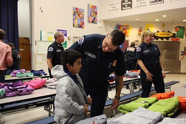 Lt. Steve Guenther with the Redmond Fire Department makes sure Daniel Hernandez’s coat fits him perfectly. Guenther was one of about 20 firefighters who visited Einstein Elementary last Friday as part of Operation Warm.