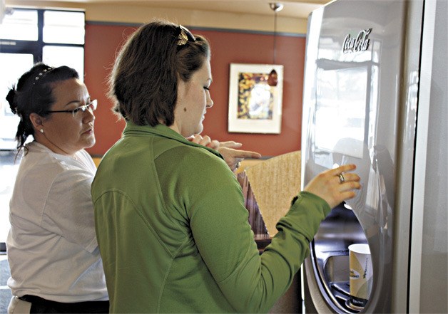 Redmond Taco Time employee Kristine Hepburn guides Rachel Ward in using the new Coca-Cola Freestyle