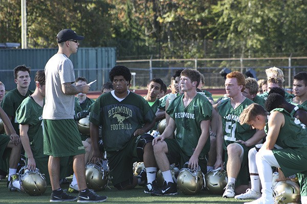 Redmond High head coach Jason Rimkus (left) discusses football-helmet safety with his players during practice last month.