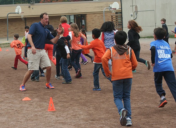 Chris Eastwood of the Orange Ruler fundraising program offers high fives to students at Louisa May Alcott Elementary School during a fun run last week. The fundraiser brought in more than $57