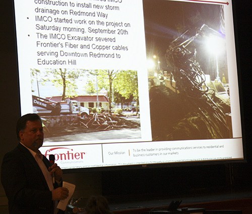 Frontier Communications' Bret Larsen speaks with customers about the outages on Wednesday night at the Redmond Community Center. Photos of the damage are shown on the screen behind him.