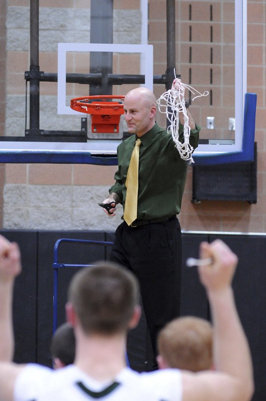 Bear Creek boys' basketball head coach Scott Moe celebrates after the ceremonial net-cutting following the Grizzlies' 53-49 Bi-District championship win over the La Conner Braves last Saturday at Chief Leschi School in Puyallup.