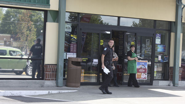 A Redmond police officer walks by one of the Safeway entrances at about 12:45 p.m. today while two employees are prepared to tell customers the store is closed because of a bomb threat.