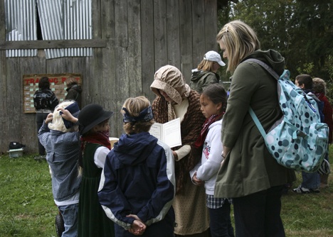 Explorer Community School teacher Susan O' Malley (wearing a pink bonnet) tells students what they'll be doing on a field trip to simulate the travels of pioneers on the Oregon Trail. O'Malley helped to develop the curriculum for the pilot program