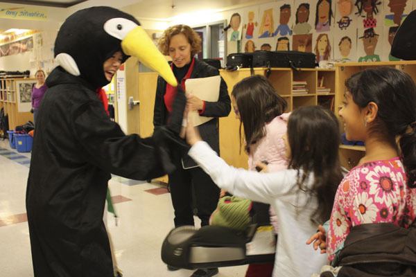 Redmond Elementary School principal Joyce Teshima greets students with high fives in her penguin suit. Teshima dressed up as the cold-weather bird after students raised $10