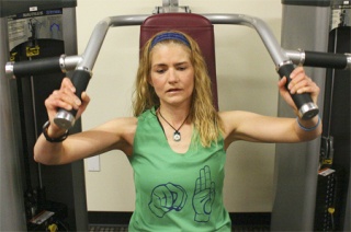 Rebecca Dufek strengthens her shoulders using an overhead press machine at Gold’s Gym in Redmond. Dufek
