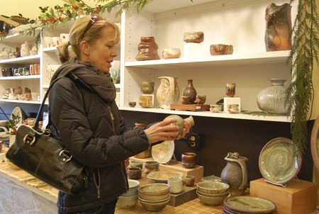 Heather Young looks at ceramic pieces by Damian Grava during last Friday's opening day of the Redmond Clay Studio’s first annual Ceramic Art Show and Holiday Sale at the Old Redmond Schoolhouse Community Center. The show will continue to run through Saturday