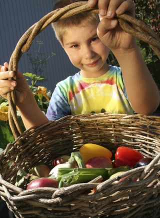 Explorer Community School student Mychal Miller shows off a collection of vegetables grown in the school's community garden. Explorer