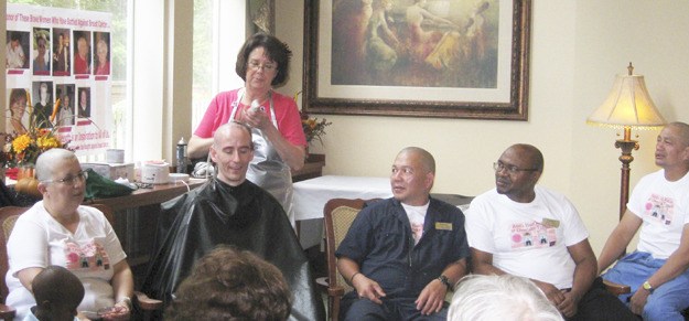 Nancy Chaney (standing) shaves the head of David Standring