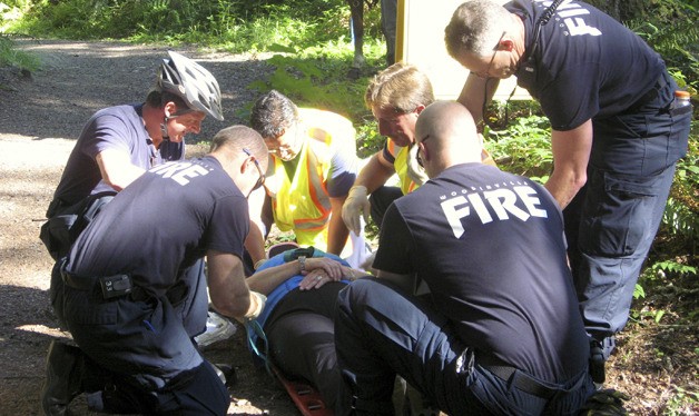 Kate Jelnicker is being attended to by responders from the Redmond and Woodinville fire departments as part of a multi-company drill Sunday morning to test the usefulness of a new trail marker system in the Trilogy at Redmond Ridge community.