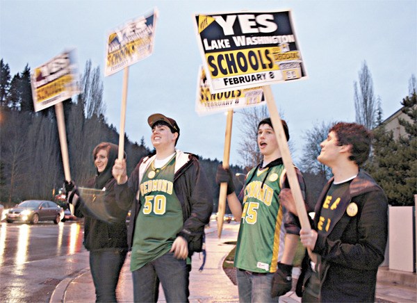 Redmond High School ASB students wave signs at the intersection of Avondale Road and Union Hill Road