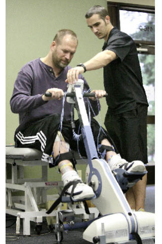 Exercise therapist Mike Buckel works with Steve Gross on an electrical stimulation bike at Pushing Boundaries