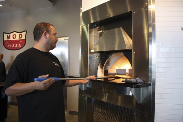 Dale Pritchard at MOD Pizza in Redmond pulls a pizza out of the restaurant’s 800-degree oven during their grand opening on Monday.