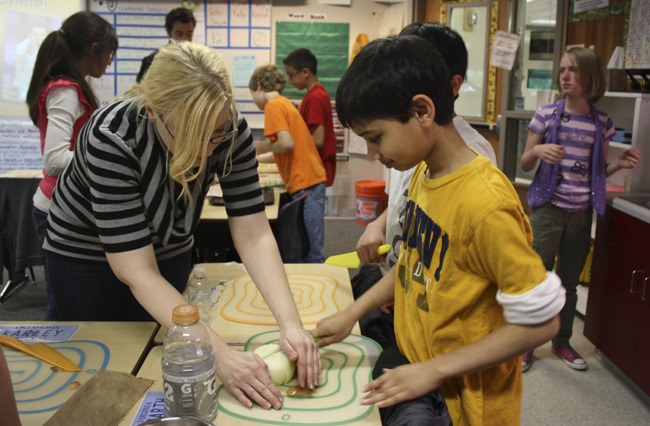 Aliyson Spence (left) shows fifth-grader Parth Parulekar how to cut an onion without hurting himself. Spence visited Albert Einstein Elementary School as part of Beecher's Flagship Foundation program