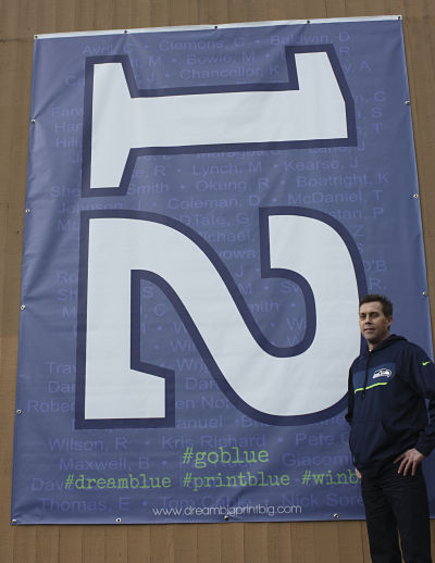 Washington Graphics president Bob Morgan Jr. stands in front of his company-made Seattle Seahawks 12th Man 8-by-10-foot sign that graces the outside of their building in Redmond.