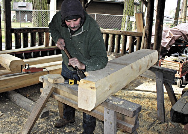 Joe Herrle of Logs and Timbers LLC carves away at a new base timber to be installed as part of the picnic shelter renovation project at historic Anderson Park in downtown Redmond. The newly restored picnic shelter