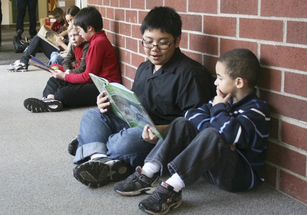 Sixth-grader Randy Un (front center with glasses) reads to first-grader Thomas Frias as part of the Hawks Can Read program at Redmond Elementary School last Friday