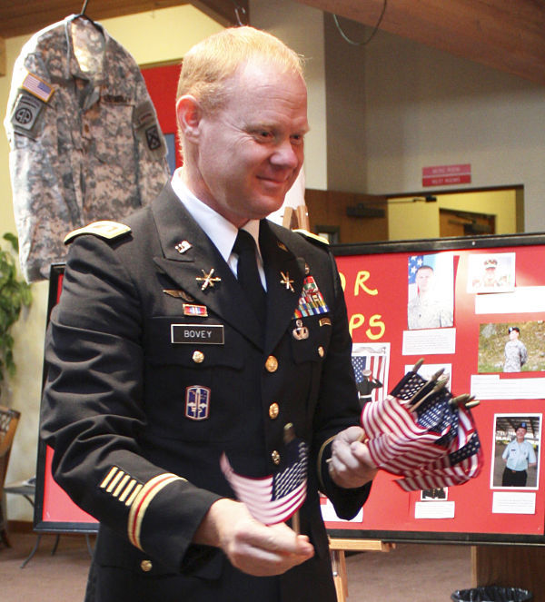 Major Charles Bovey of the U.S. Army hands out miniature American flags this morning at the Faith Lutheran School of Redmond's Veterans Day ceremony.