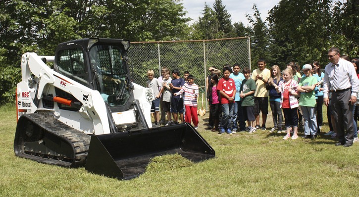 Benjamin Rush Elementary School teacher Syd Mack drives a bulldozer as a treat for students during a groundbreaking ceremony for the school's new building. Mack has been with the school since it opened in 1970. At 65