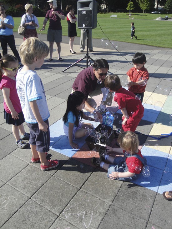 Redmond resident Mitch Lee Yuen is surrounded by young children playing with the bubble machine
