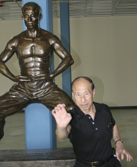 World-renowned martial arts Master John S.S. Leong strikes a pose in front of a statue given to him by grateful students