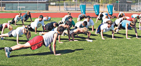 The Redmond High cross country team warms up with some push-ups prior to practice at Redmond High last week. The girls' squad looks particularly strong this year