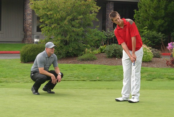 Redmond golf coach Chris Zimmerman helps Daniel Bies line up a putt during a recent practice at Bear Creek Country Club. The Mustangs return four players that made the state tournament last year