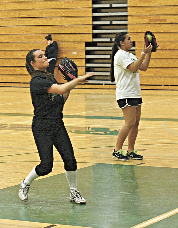 Varsity senior co-captains Stephanie Gero (left) and Christine Ho lead the Mustangs fastpitch squad through a throwing drill during a recent indoor practice in the Redmond High School gym. Gero