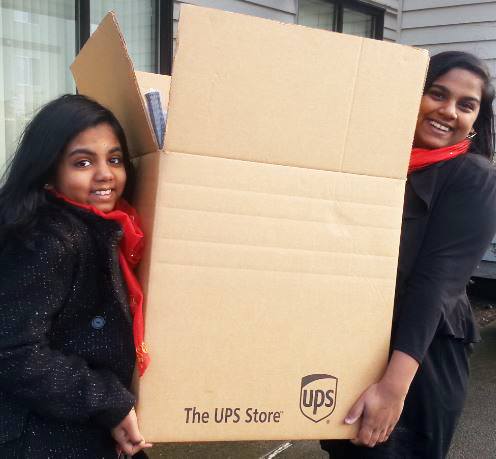 Sarah Rachna Thomas (left) and Sneha Ruth Thomas carry a box full of gifts donated by neighbors to go to local foster children.