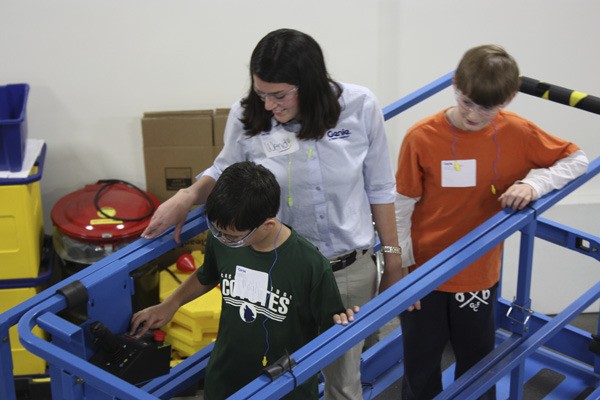 Noah Benitez (left) operates a Genie scissor lift as engineer Gwendoly Espe and Tyler Runyan watch. Noah and Tyler visited Genie in Redmond for research on a robotics project.