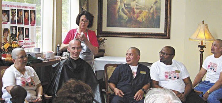 Nancy Chaney (standing) shaves the head of David Standring