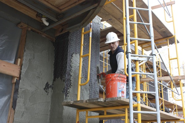 A worker applies stucco to the side of the building that will be BJ's Restaurant and Brewhouse in Redmond Town Center.