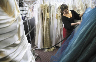 Ruth Garcia uses a steamer to remove wrinkles from a dress at Amanda’s Bridal Boutique. Amanda Haines