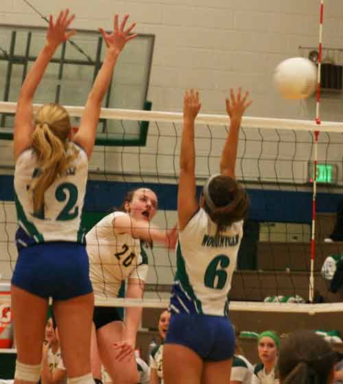Redmond High’s Audrey Hyem spikes the ball past a pair of Woodinville High players on Monday night.