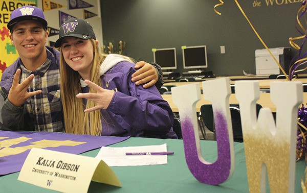 Redmond High’s Brendan Ecklebarger and Kaija Gibson flash the University of Washington sign today at a baseball and softball signing event in the school Career Center.
