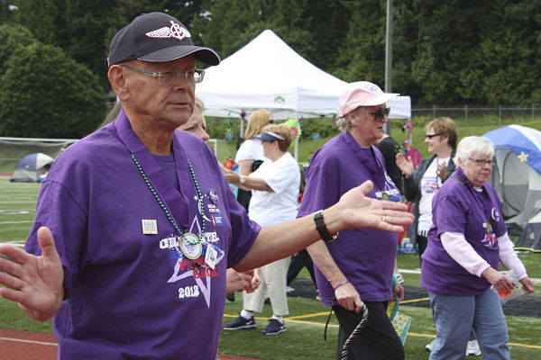 Redmond's Lyle Burns claps to the music while walking in the cancer survivors' lap at the Relay for Life of Redmond/Kirkland's event to benefit the American Cancer Society last Saturday at Redmond High.
