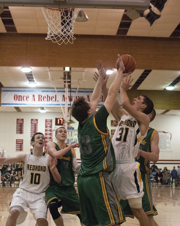 Mustang senior Leslie Ellis drives to the hoop and draws contact while fellow senior Jason Harrington (left) watches. Ellis and Harrington both had older brothers (Will and Chris) that started for Redmond’s 5th-place state team in 2009