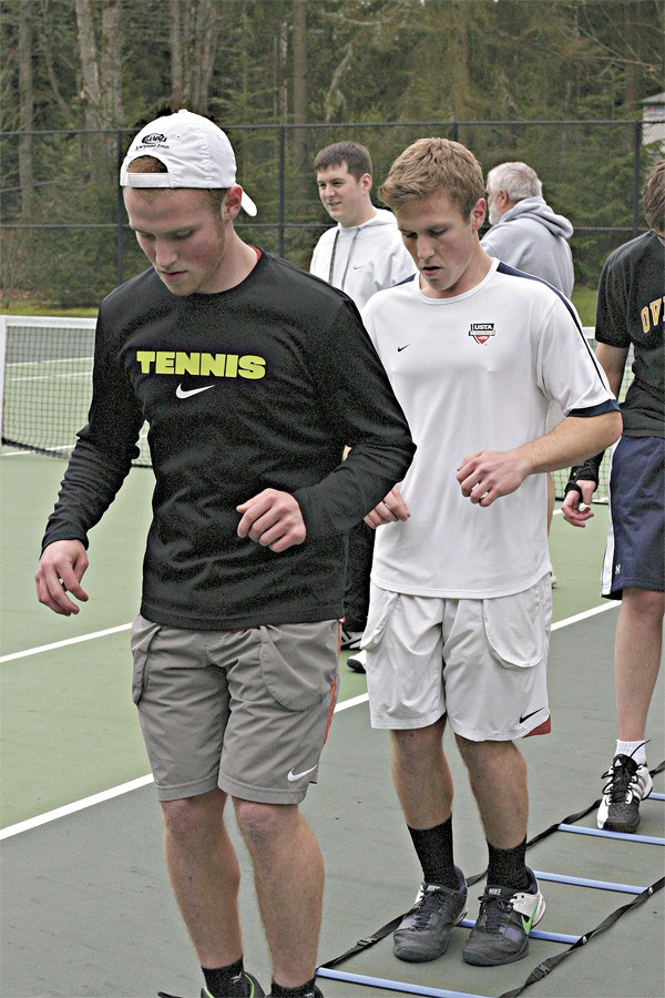 Overlake School boys' tennis co-captains Grant (left) and Marcus Munoz lead the team through a conditioning exercise at a recent practice. In their senior year