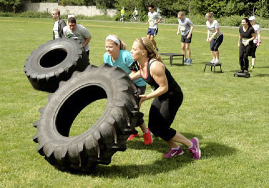 Serious About Fitness 8K walk/run participants roll through the tire exercise.