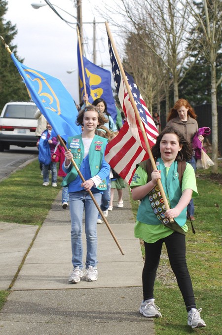 Horace Mann Elementary Girl Scouts Dee Dee Lennon-Jones (left) carries the Girl Scouts flag while Kirsten Moynihan leads Wednesday’s parade of nations with the American flag. The parade was part of World Thinking Day