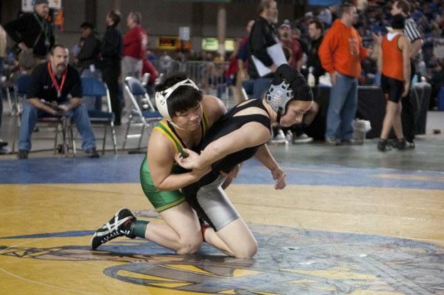 Redmond senior Catherine Kelly (left) takes down Kentwood's Cassidy Meyers in the consolation semifinals of the girls' 119 weight class at Mat Classic XXIII last Saturday at the Tacoma Dome. Kelly lost to Meyers 7-4 en route to a 6th place finish.