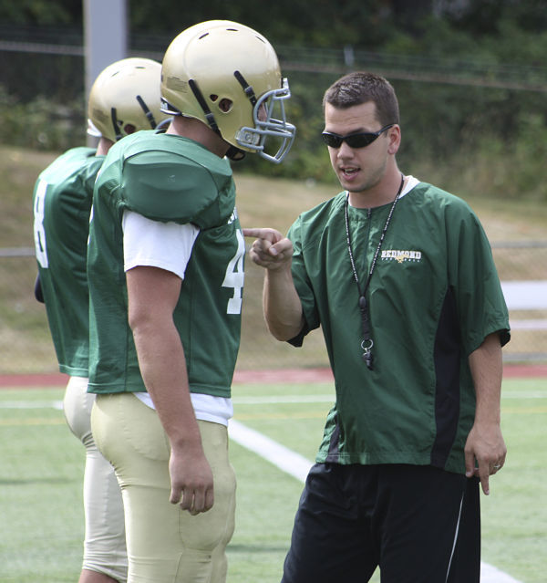 New Redmond High School football coach Jason Rimkus instructs a player during a break in a hitting drill on Monday afternoon.