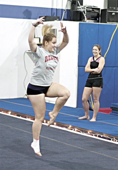 Senior Marjorie Drieu works on her 'Cat Leap 1/1 turn' floor exercise while senior co-captain Maria Di Iorio looks on during a recent Mustang gymnastics practice at Eastside Gymnastics Academy in Woodinville.