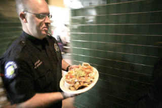 Redmond police officer Matthew Hurley carries a plate of food at Claim Jumper last Thursday. Hurley was one of several officers who volunteered to serve at the restaurant during the Tip-A-Cop event to benefit Special Olympics.