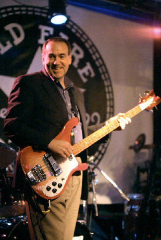 Former governor of Arkansas and former 2008 presidential primary contender Mike Huckabee grins at the crowd as he plays bass guitar on stage at the Old Fire House Teen Center last Thursday night. Huckabee was the headliner for the Music Aid Northwest event. For story and more photos