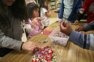 Sisters Maya and Selina Adelman work with other students at a beading “creation station