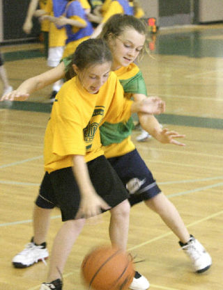 ABOVE: Caleigh Sweeters (in green) guards Maddie Egberg as the “Rubber Duckies” and the “Macadamia Nuts” scrimmaged during a girls basketball camp at Redmond High last Wednesday. BELOW: Molly Brown (in green) tries to work her way down the court and around Stephanie Kinssies during camp action at RHS.