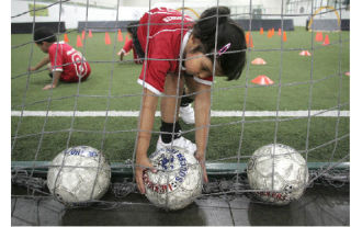 Asha Behrman grabs a soccer ball from the net during an Arena Sports Lil’ Kickers