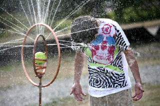 Dillon Jarvis attempts to beat the heat by getting doused by a double hoop copper sprinkler