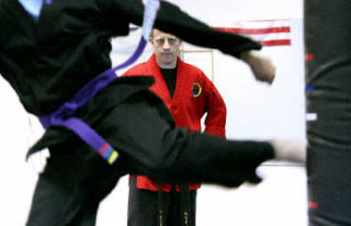 Instructor John Andrews watches as a student kicks a bag during an intermediate martial arts class at Washington Black Belt Academy. The school will be holding a kidnap prevention event on Saturday.